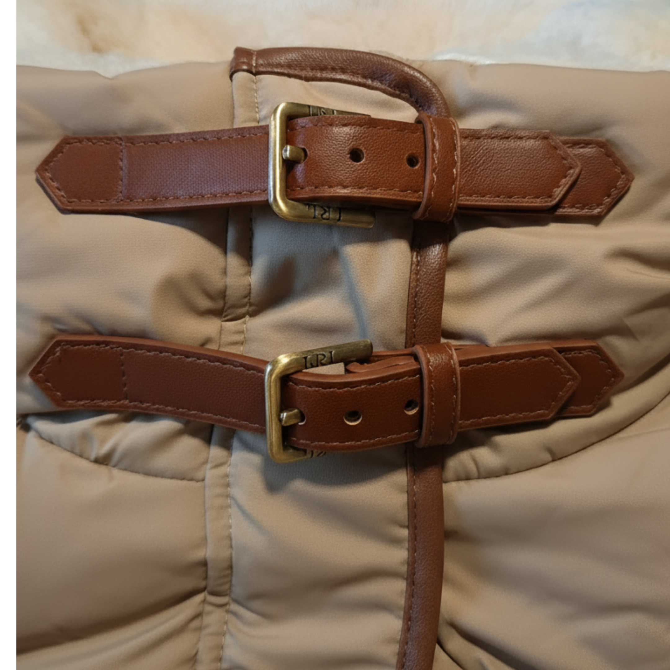 Close-up of a brown leather belt with brass buckle on beige fabric.