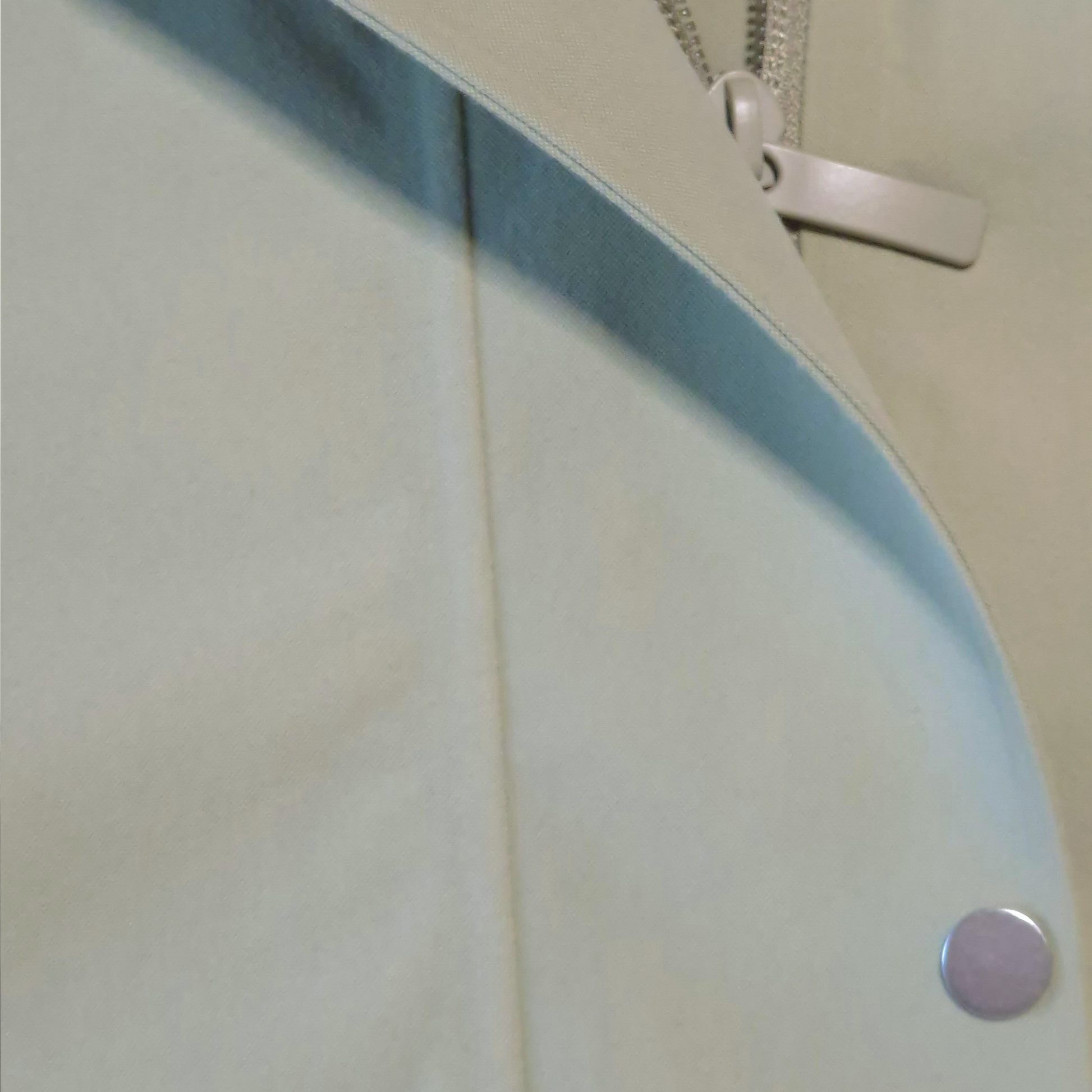 Close-up of lululemon rain jacket in a zipper and button detail.