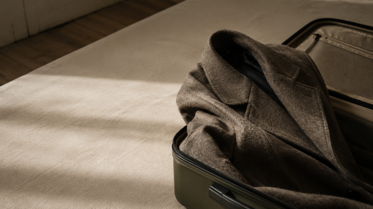 Winter coat packed inside an open suitcase for a cold-weather trip
