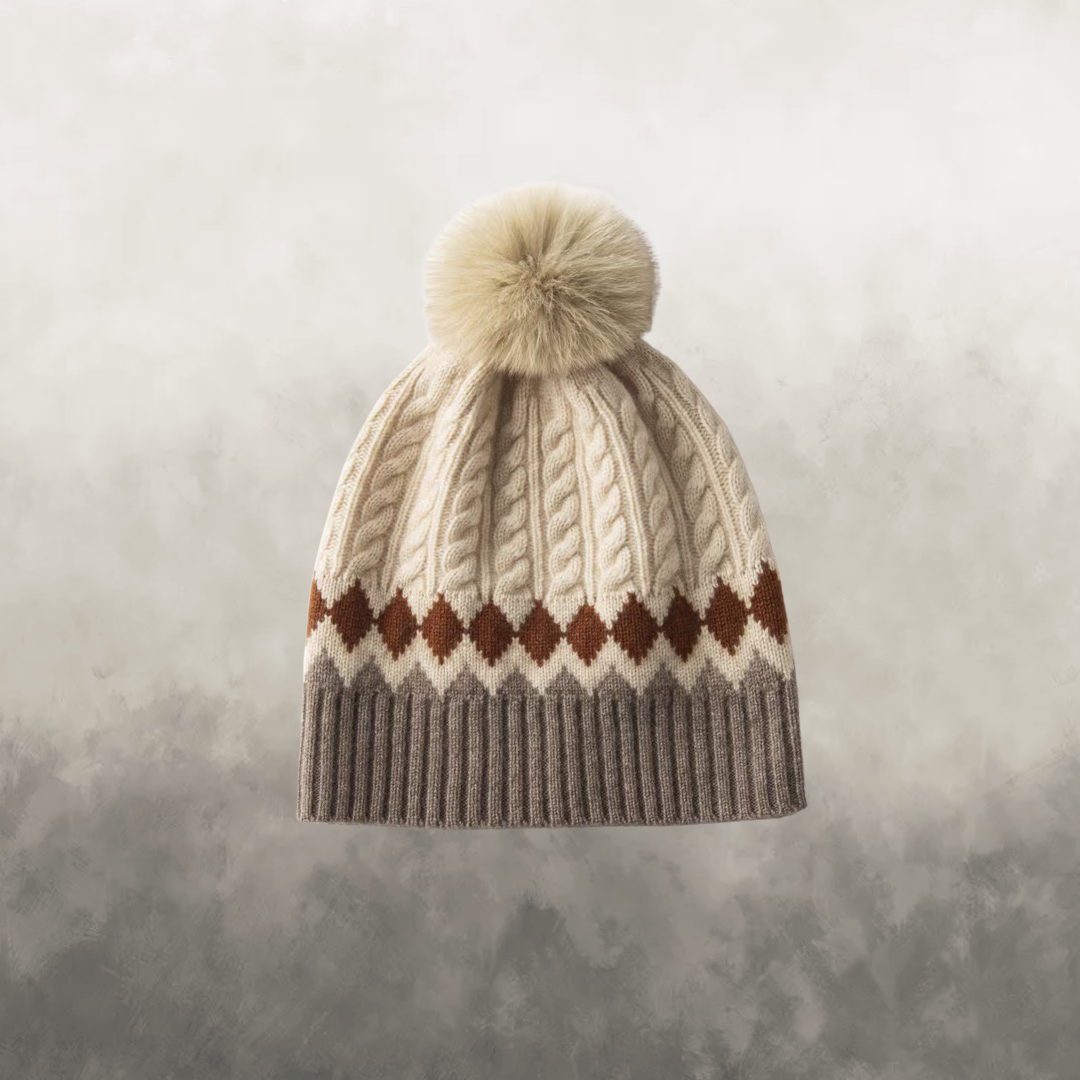 Knitted beanie with pom-pom and diamond pattern on a textured gray background
