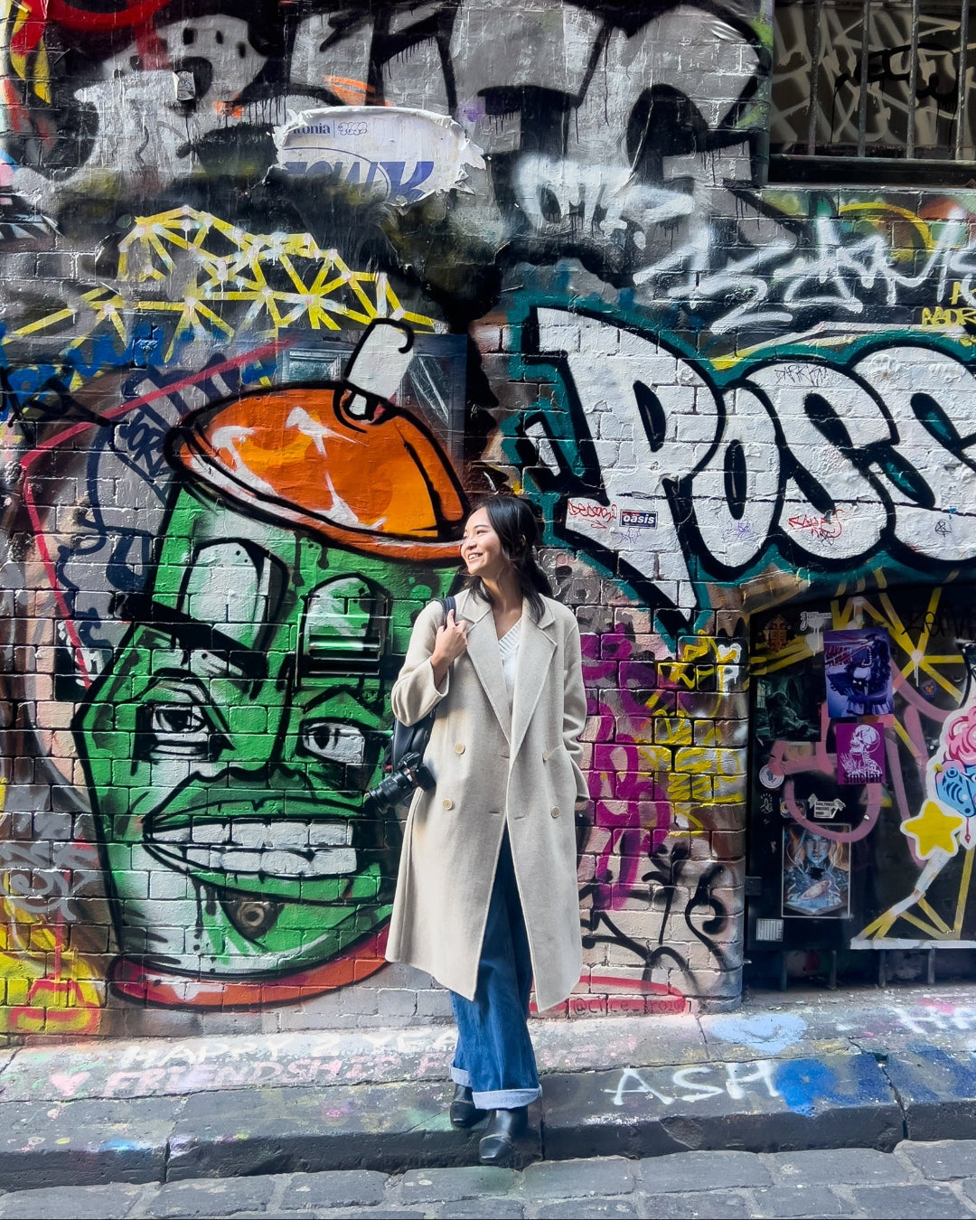Woman standing in front of a colorful graffiti-covered wall.