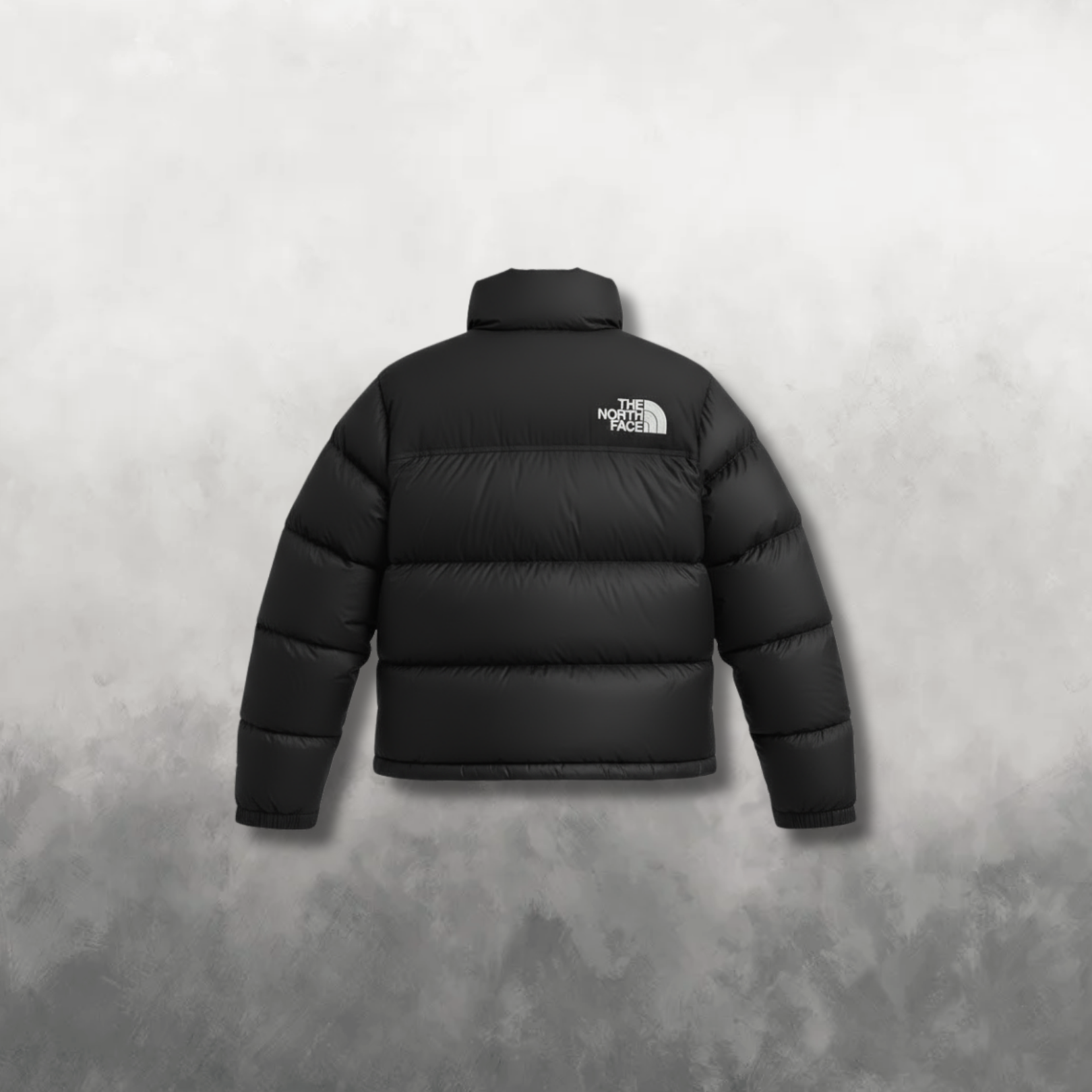 Black puffer jacket with The North Face logo on a gray background