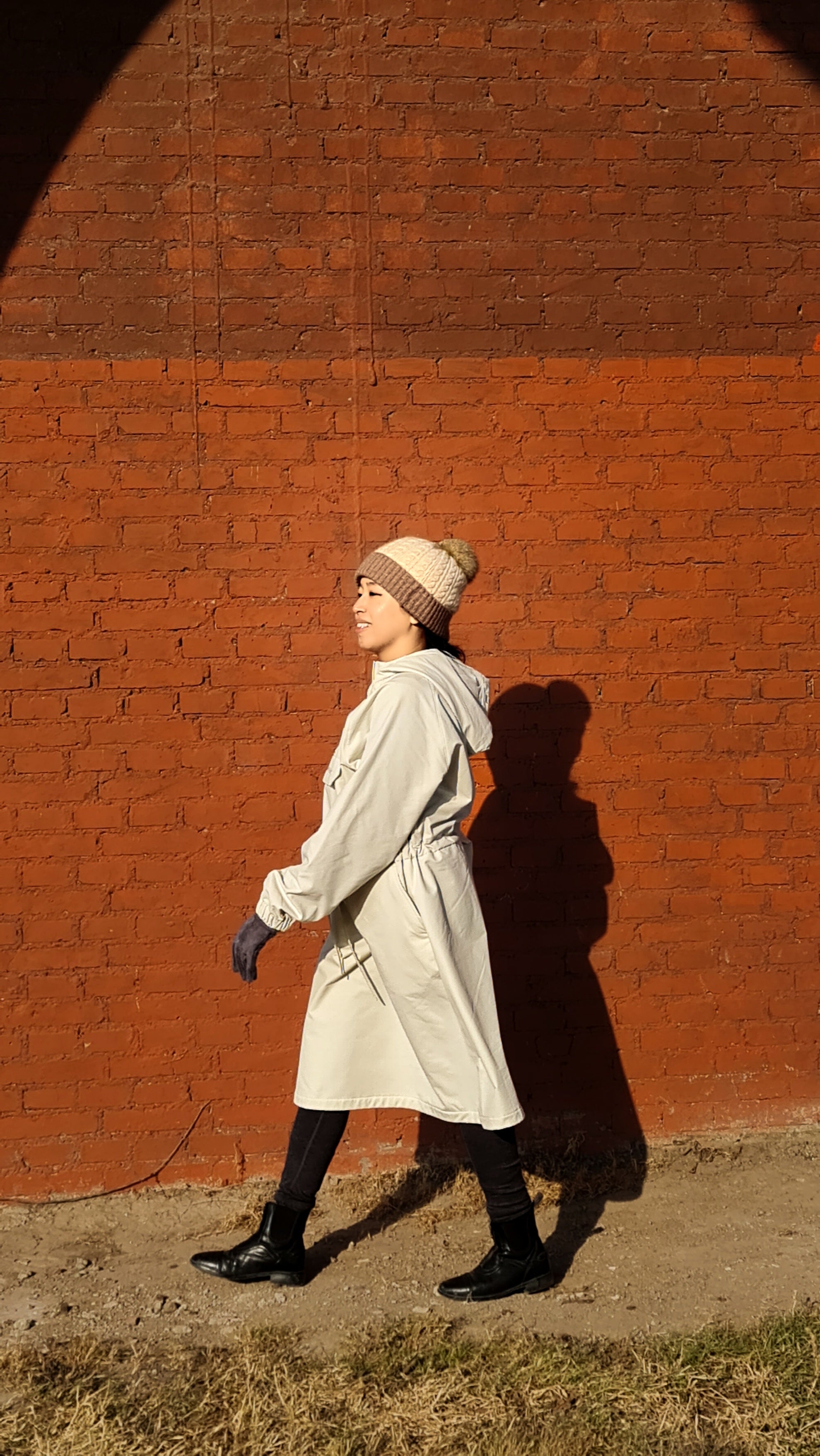Person wearing a National Geographic Warm Fleece Woven Dress in Cream walking beside a red wall