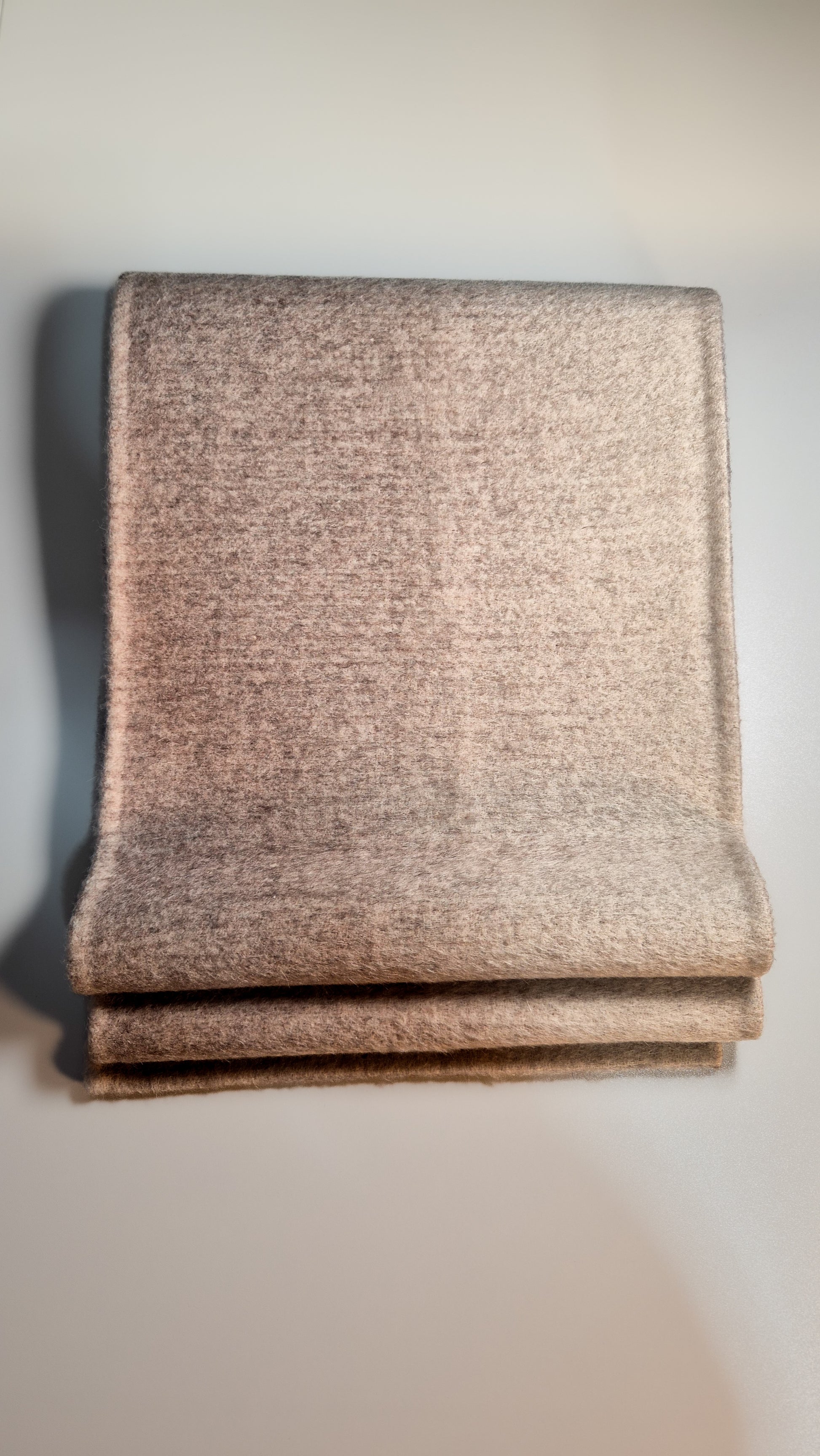 Folded beige scarf on a light gray background